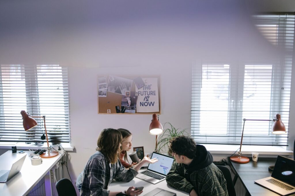 A group of people discussing ideas around laptops in a modern office